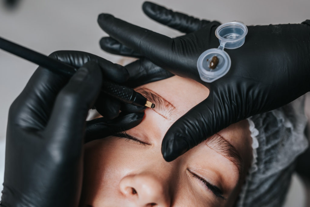 microblading artist performing microblading service on woman